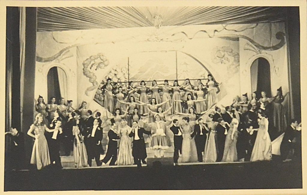 fotografie-teatru-de-revista-interbelic-ansamblu-perechi-plus-grup-de-femei-femeia-din-mijloc-are-bratele-deschise